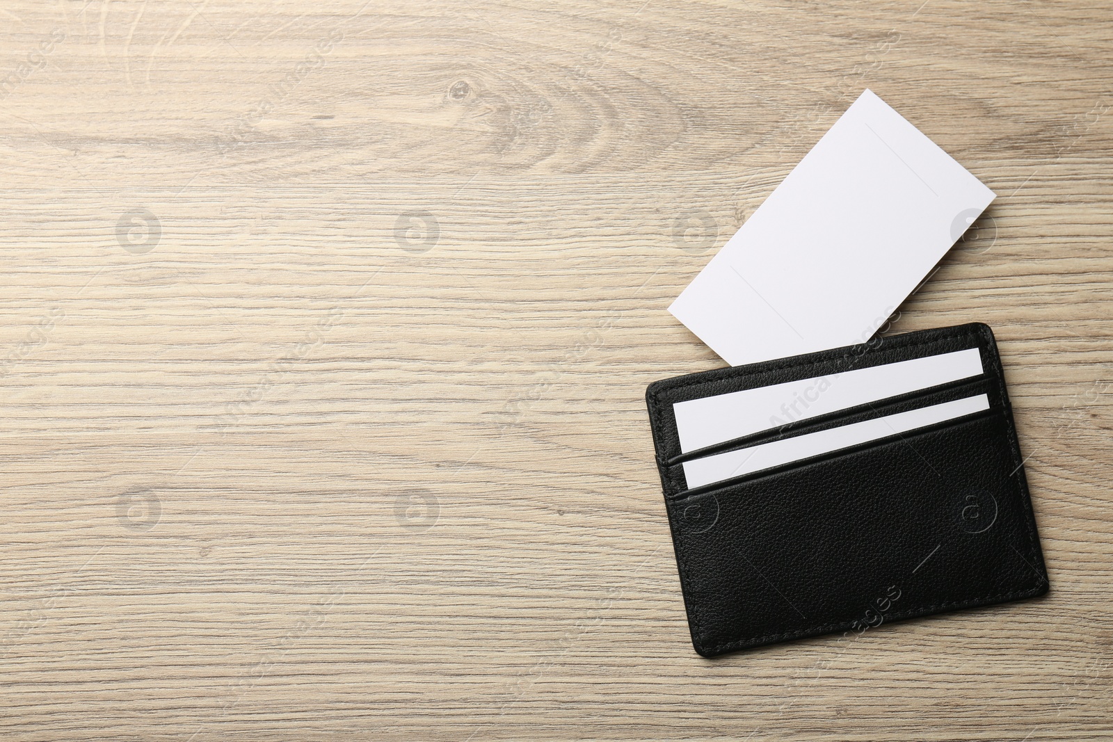 Photo of Leather business card holder with blank cards on wooden table, top view. Space for text