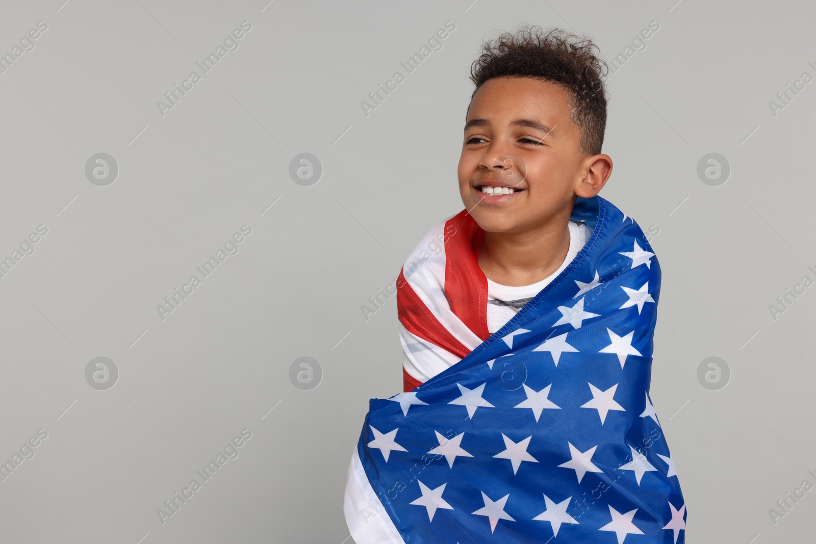 Photo of 4th of July - Independence Day of USA. Happy boy with American flag on light grey background, space for text