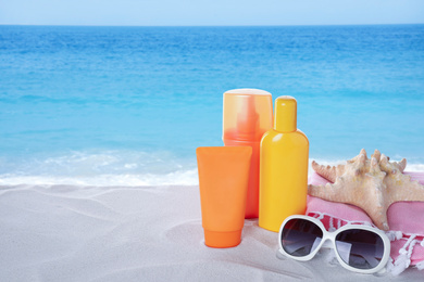 Image of Set of sun protection products and stylish sunglasses on sandy beach. Space for text