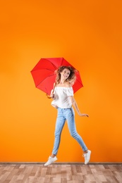 Woman with red umbrella near color wall