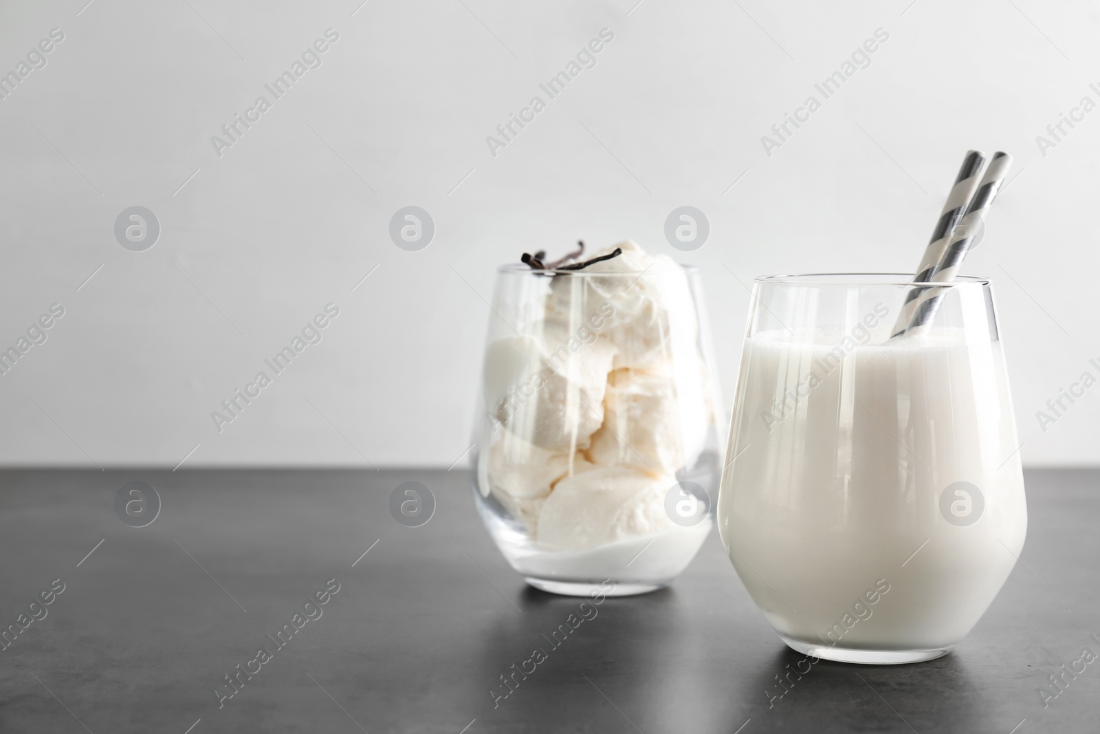 Photo of Glasses with milk shake and tasty vanilla ice cream on grey table