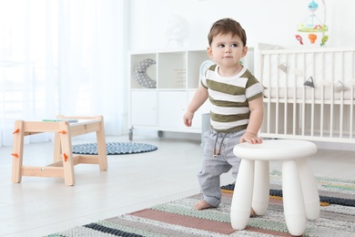 Cute baby holding on to stool at home.  Learning to walk