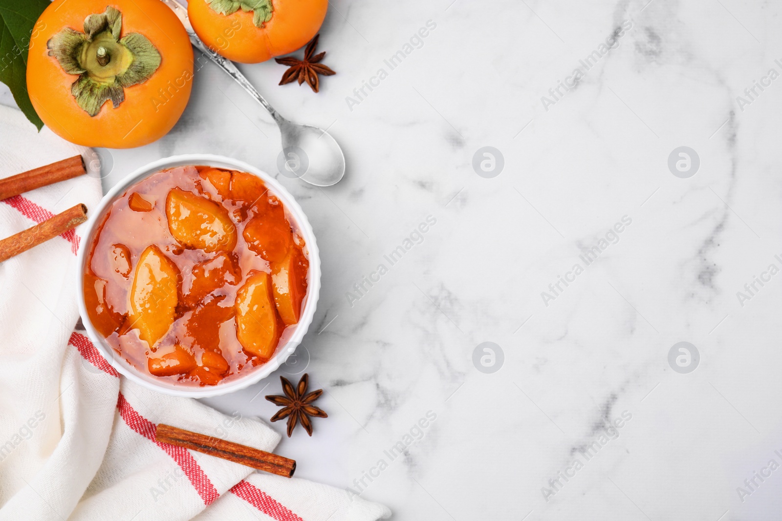 Photo of Bowl of tasty persimmon jam on white marble table, flat lay. Space for text