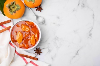 Photo of Bowl of tasty persimmon jam on white marble table, flat lay. Space for text