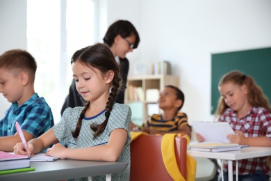 Adorable little children sitting at desks in classroom. Elementary school