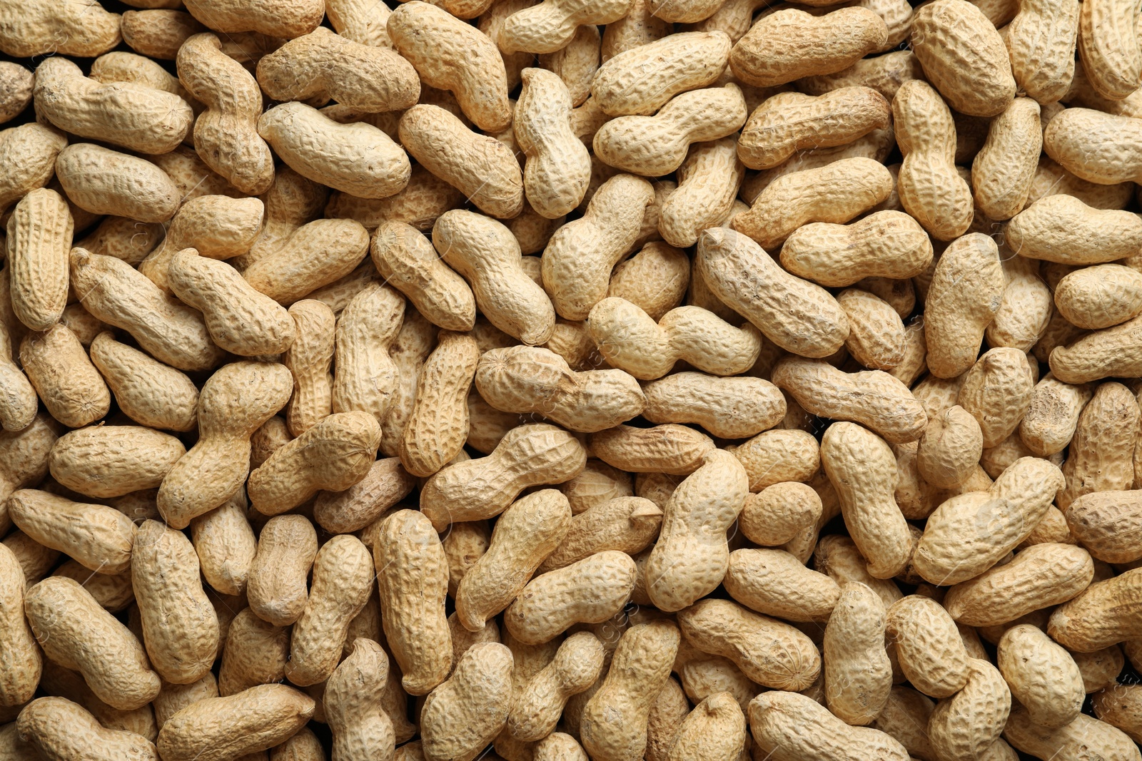 Photo of Many fresh unpeeled peanuts as background, top view