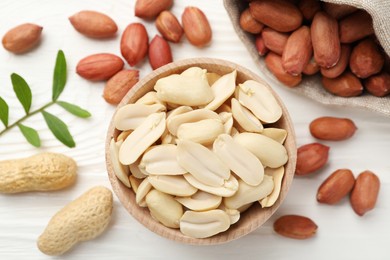 Fresh peanuts and twig on white wooden table, flat lay