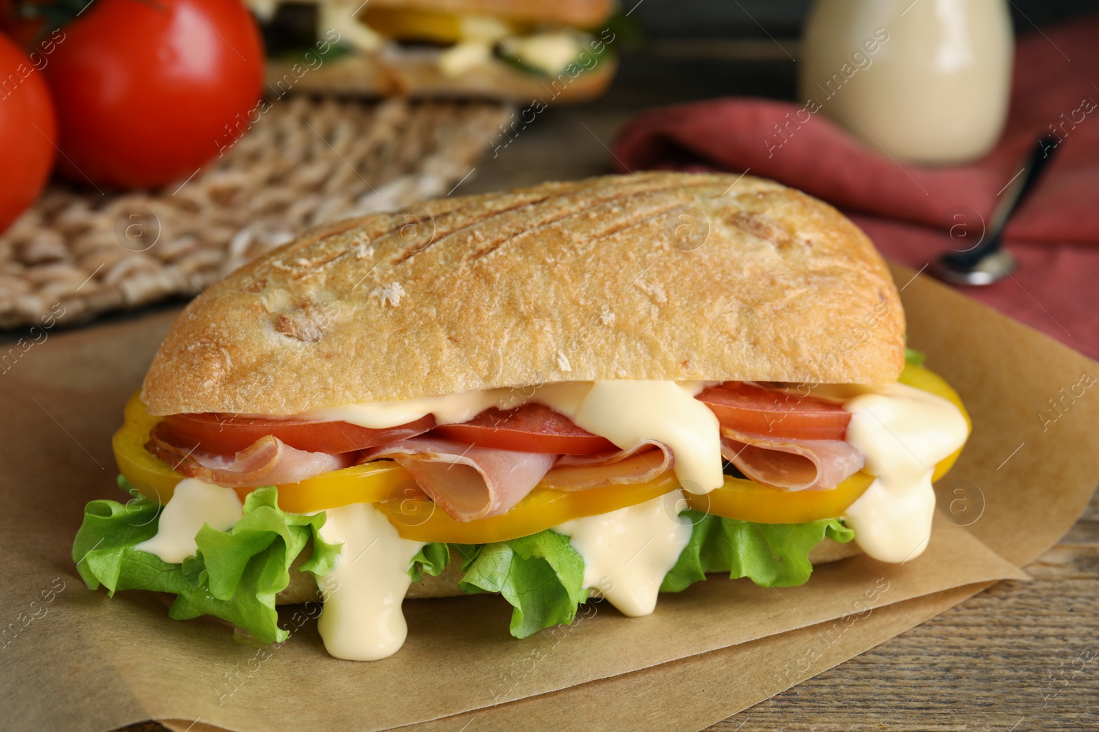 Photo of Delicious sandwich with vegetables, ham and mayonnaise served on wooden table, closeup