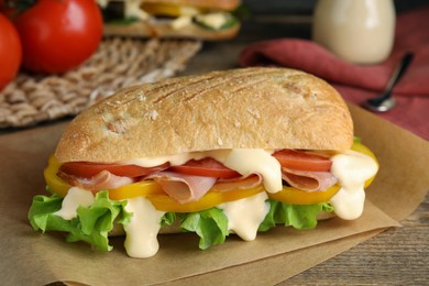 Photo of Delicious sandwich with vegetables, ham and mayonnaise served on wooden table, closeup