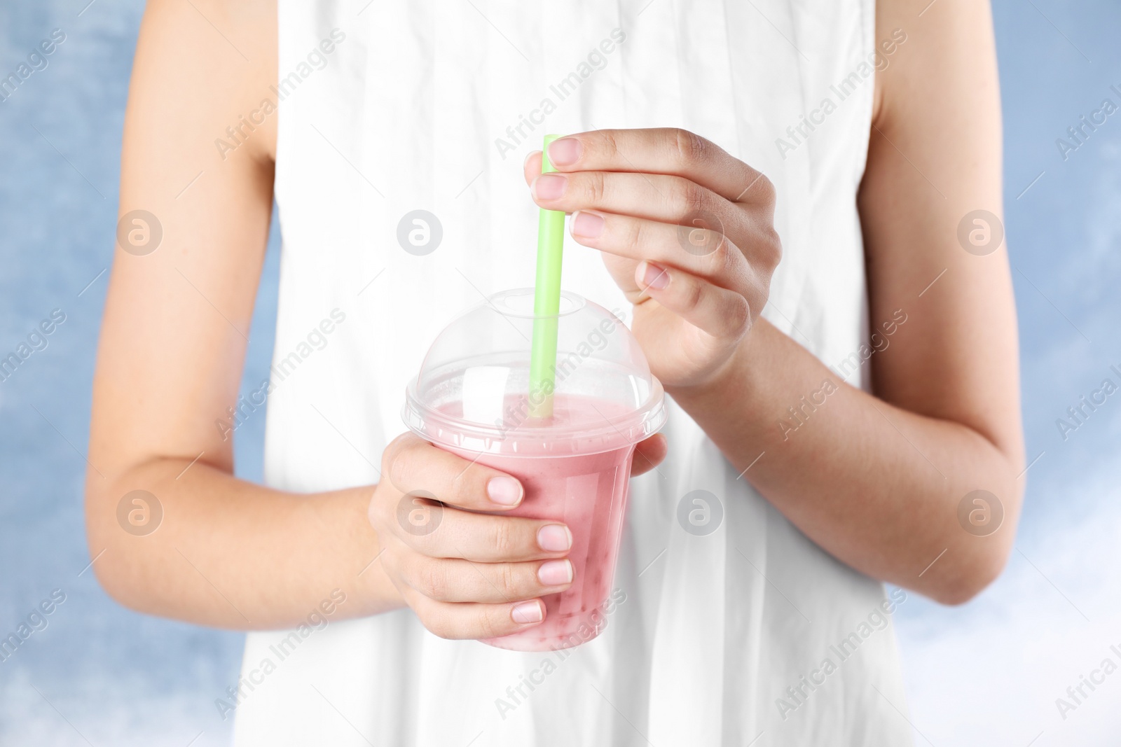 Photo of Woman with tasty milk shake on blue background, closeup