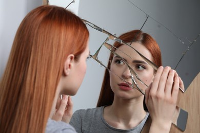 Photo of Sad young woman suffering from mental problems near broken mirror
