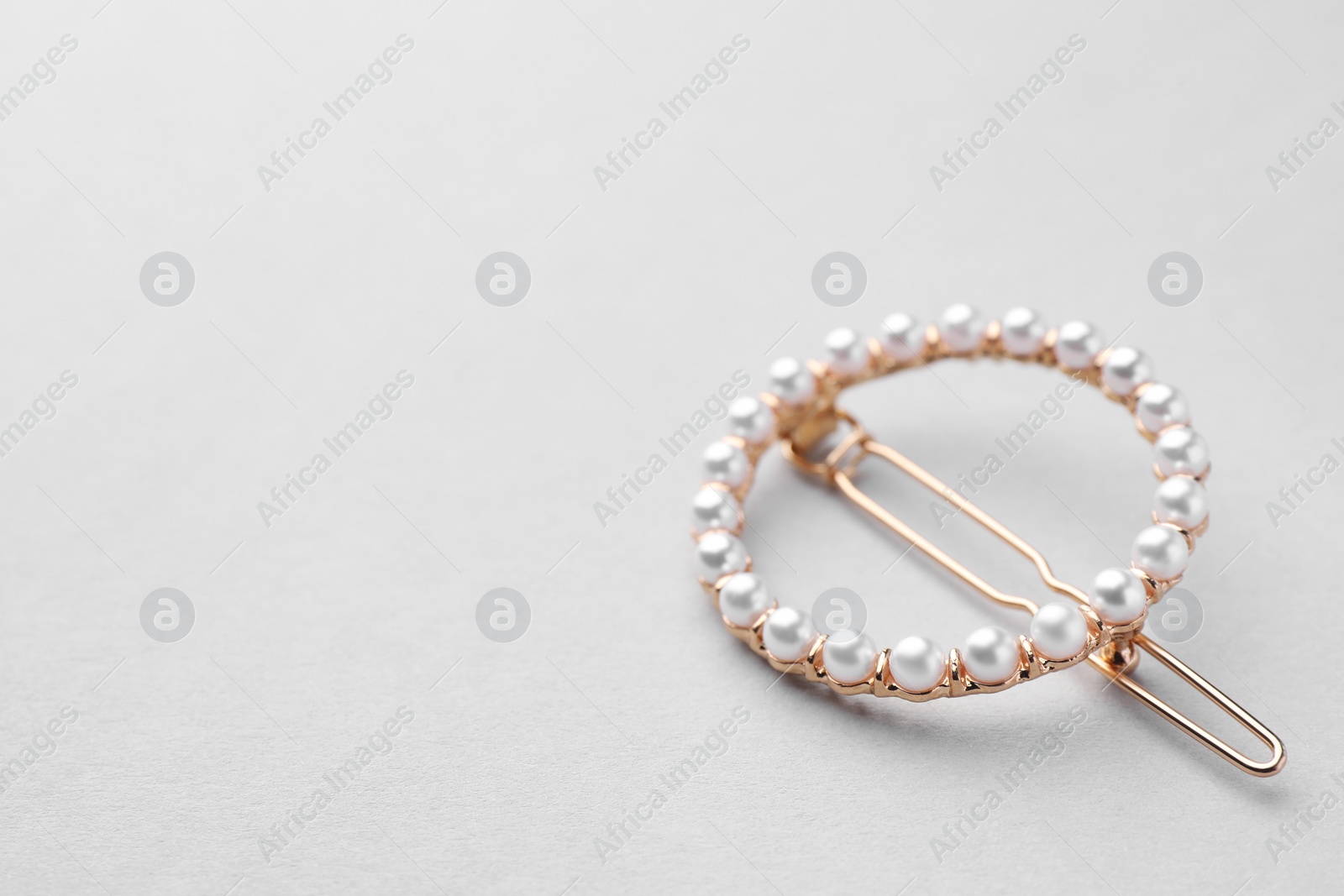 Photo of Elegant pearl hair clip on white background. Space for text