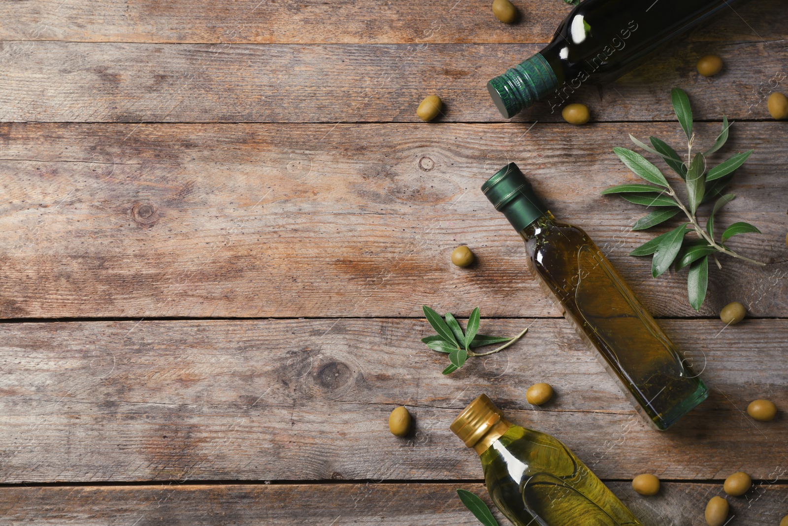 Photo of Flat lay composition with bottles of olive oil and space for text on wooden background