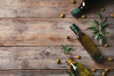 Flat lay composition with bottles of olive oil and space for text on wooden background