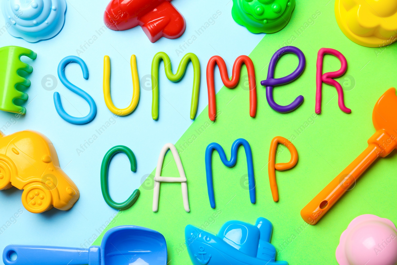 Photo of Text SUMMER CAMP made of modelling clay and different sand molds on color background, flat lay