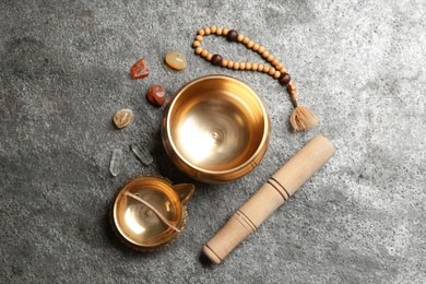 Flat lay composition with golden singing bowl on grey table. Sound healing