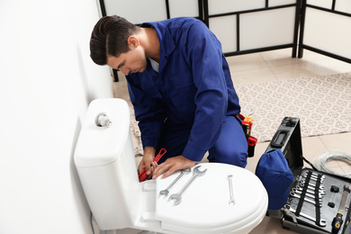 Photo of Professional plumber working with toilet bowl in bathroom