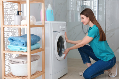 Woman near washing machine in bathroom. Laundry day