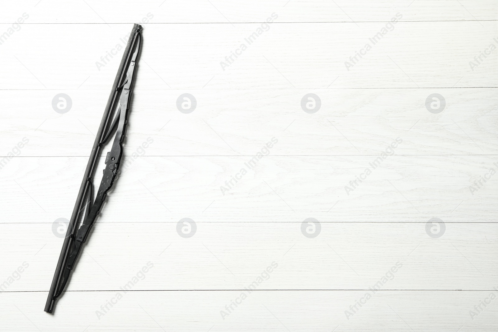 Photo of Car windshield wiper on white wooden background. top view. Space for text