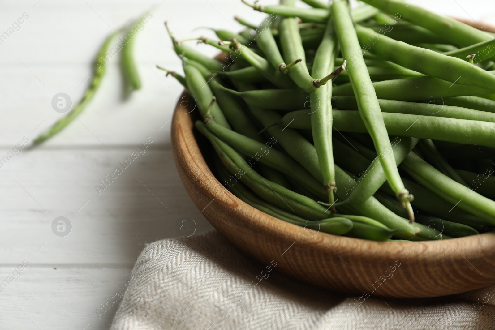 Photo of Fresh green beans in bowl on white wooden table, closeup