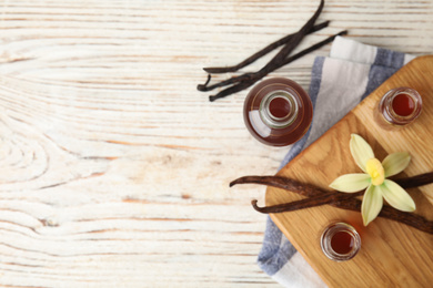 Flat lay composition with vanilla extract on white wooden table. Space for text