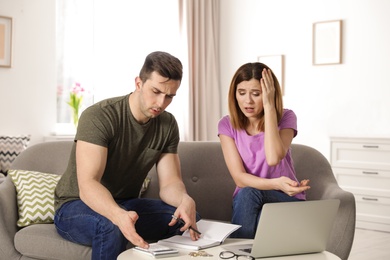 Sad couple counting money in living room