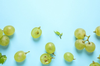 Flat lay composition with fresh ripe juicy grapes on light blue background, space for text