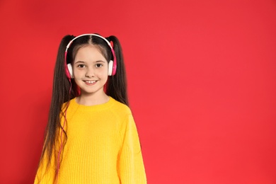Photo of Cute girl enjoying music in headphones on color background. Space for text