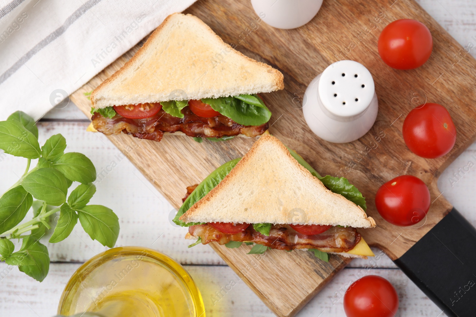 Photo of Delicious sandwiches with fried bacon, spices and products on wooden rustic table, flat lay