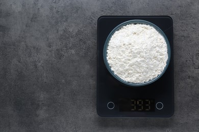 Electronic scales with flour on grey table, top view. Space for text