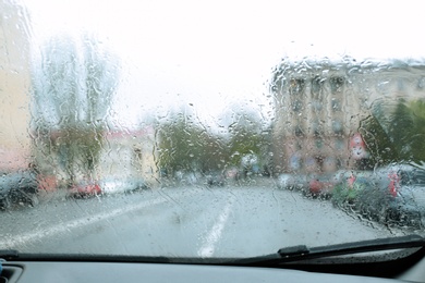 Blurred view of road through wet car window. Rainy weather