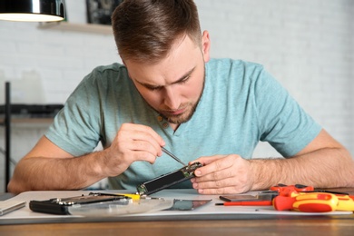 Technician repairing mobile phone at table in workshop