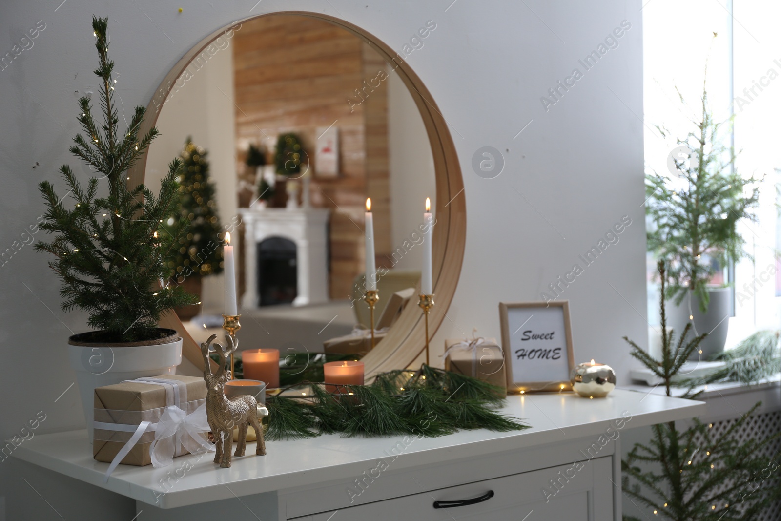 Photo of Mirror over chest of drawers with Christmas decor in room. Interior design