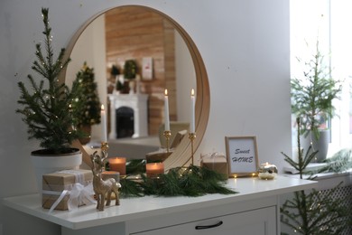 Mirror over chest of drawers with Christmas decor in room. Interior design