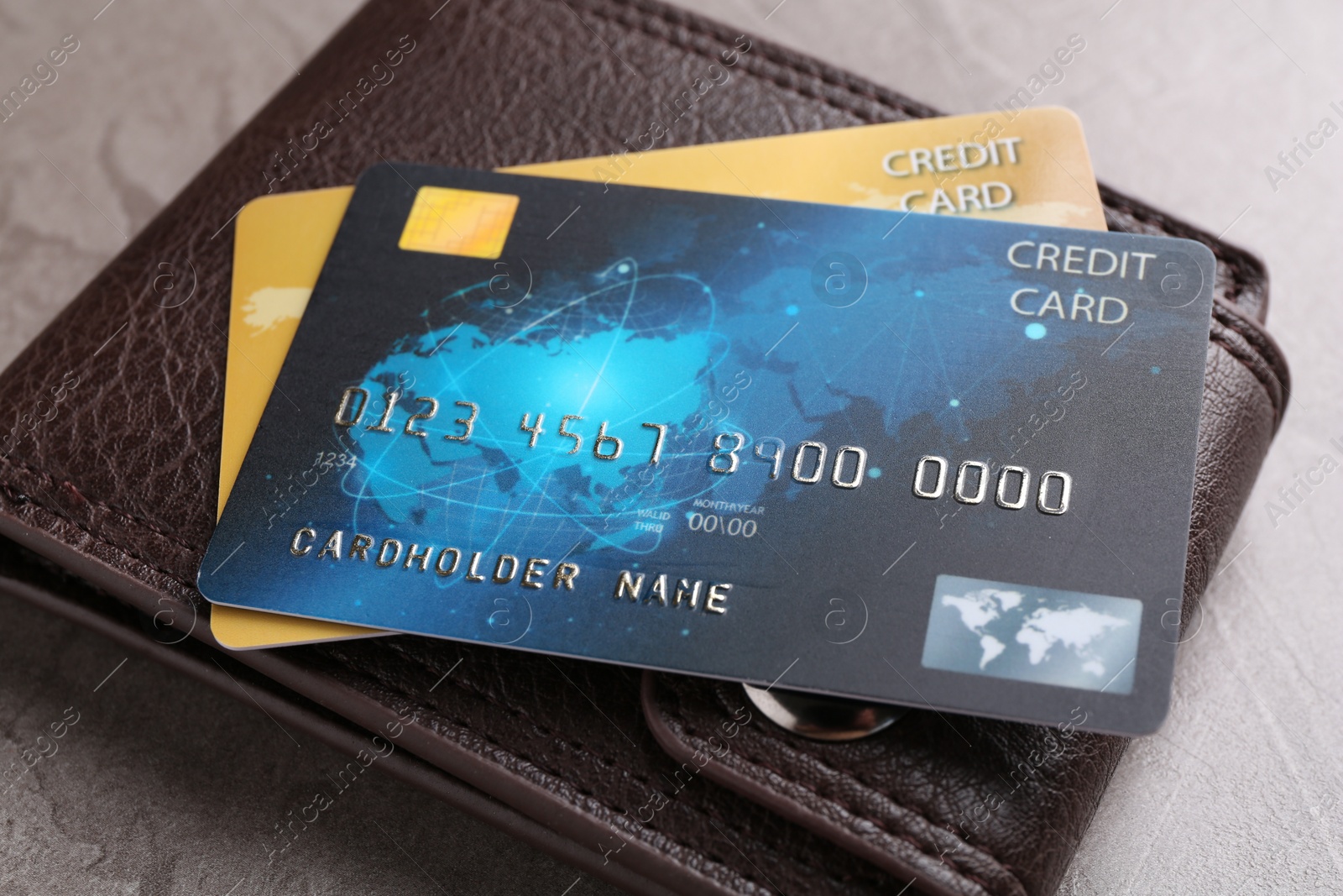 Photo of Credit cards and leather wallet on grey textured table, closeup