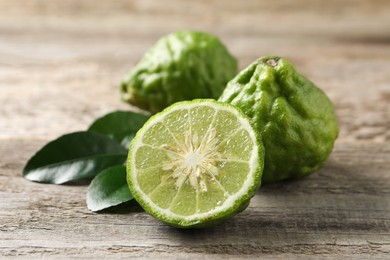 Fresh ripe bergamot fruits with green leaves on wooden table, closeup