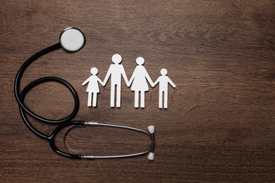 Photo of Paper family cutout and stethoscope on wooden background, flat lay with space for text. Insurance concept
