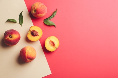 Photo of Fresh ripe peaches and green leaves on color background, flat lay. Space for text