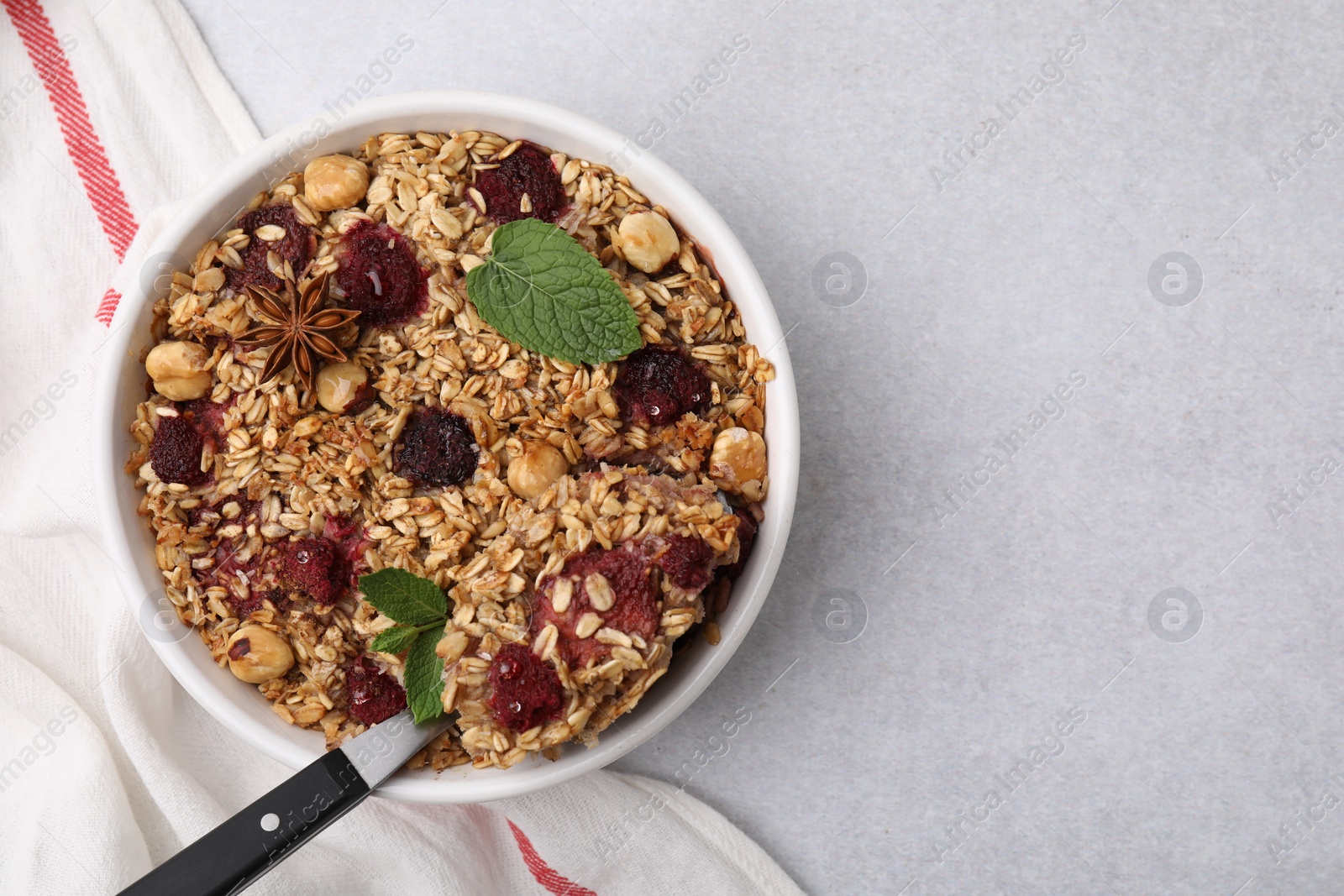 Photo of Tasty baked oatmeal with berries, nuts and anise star on light grey table, top view. Space for text