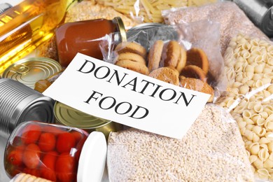 Photo of Card with words Donation Food and different products on table, closeup