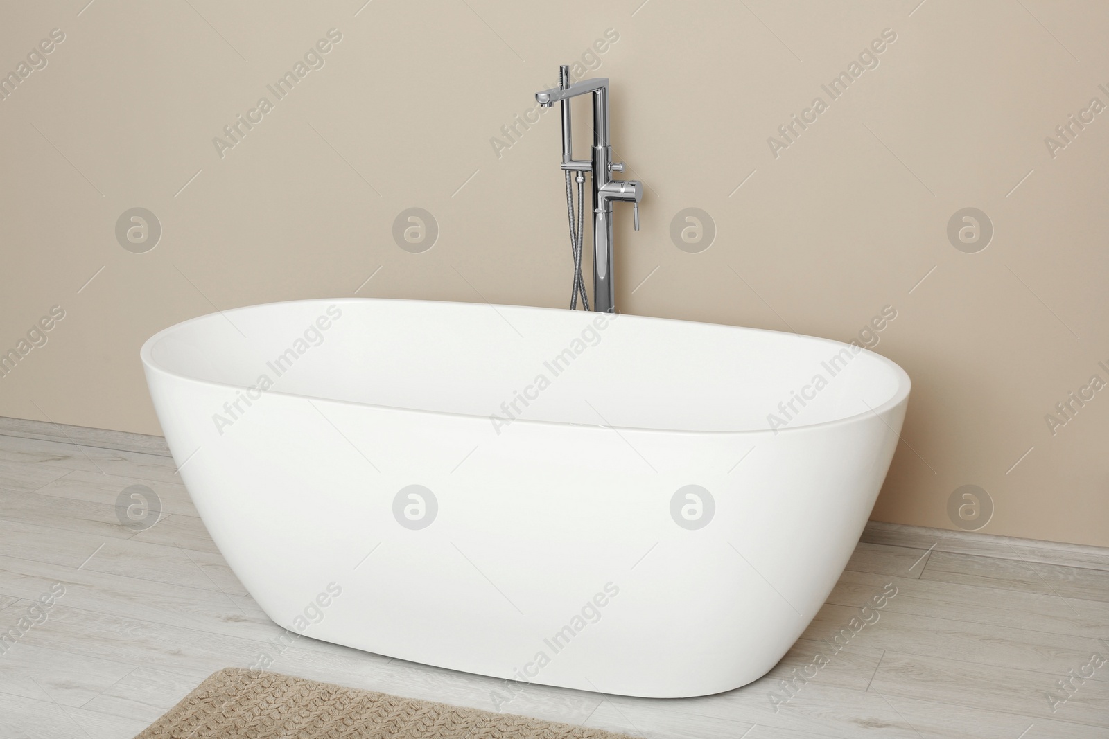 Photo of Beautiful white tub near beige wall in bathroom. Interior design