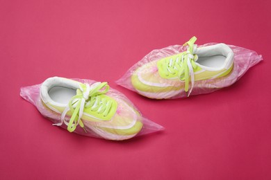 Photo of Sneakers in shoe covers on pink background, above view