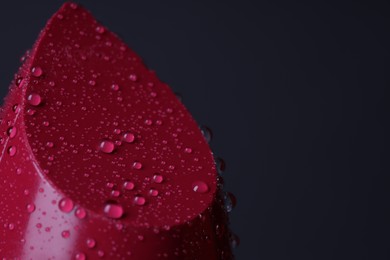 Photo of Red lipstick with water drops on dark gray background, macro view. Space for text