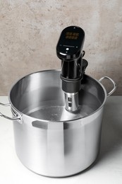 Thermal immersion circulator in pot on white table. Sous vide cooker