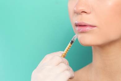 Young woman getting lips injection on color background, space for text. Cosmetic surgery