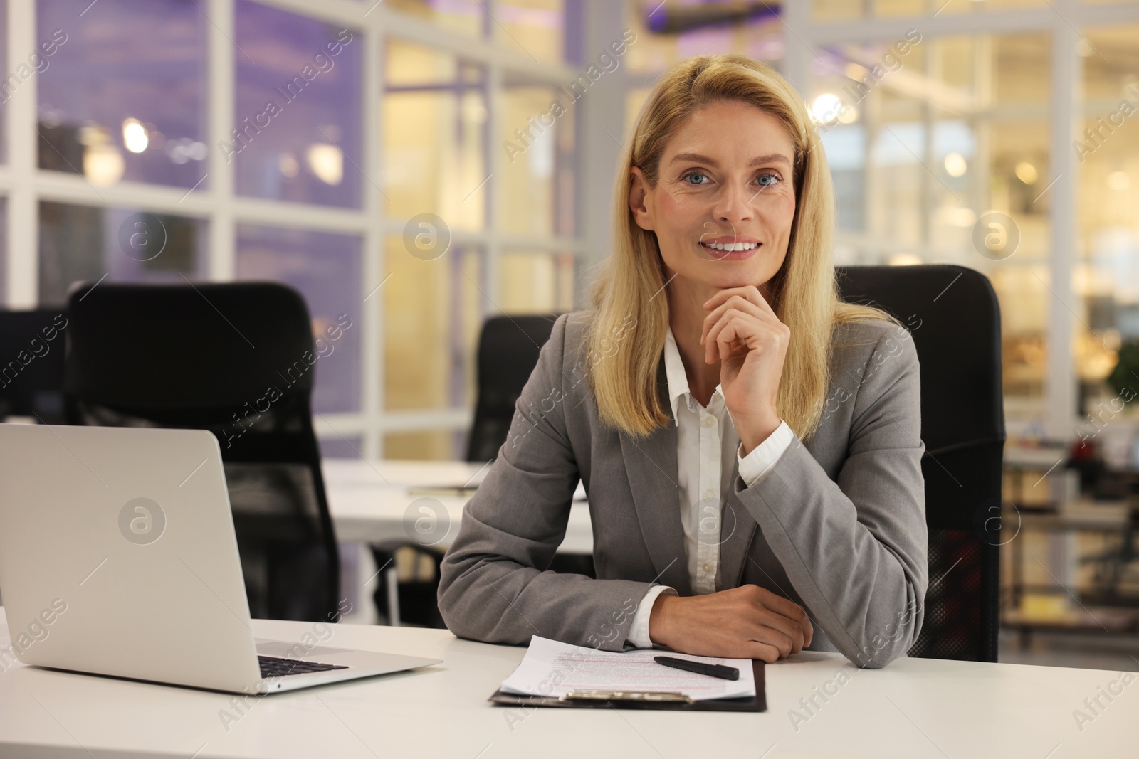 Photo of Smiling woman working at table in office. Lawyer, businesswoman, accountant or manager