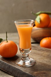 Photo of Delicious tangerine liqueur and fresh fruits on table, closeup