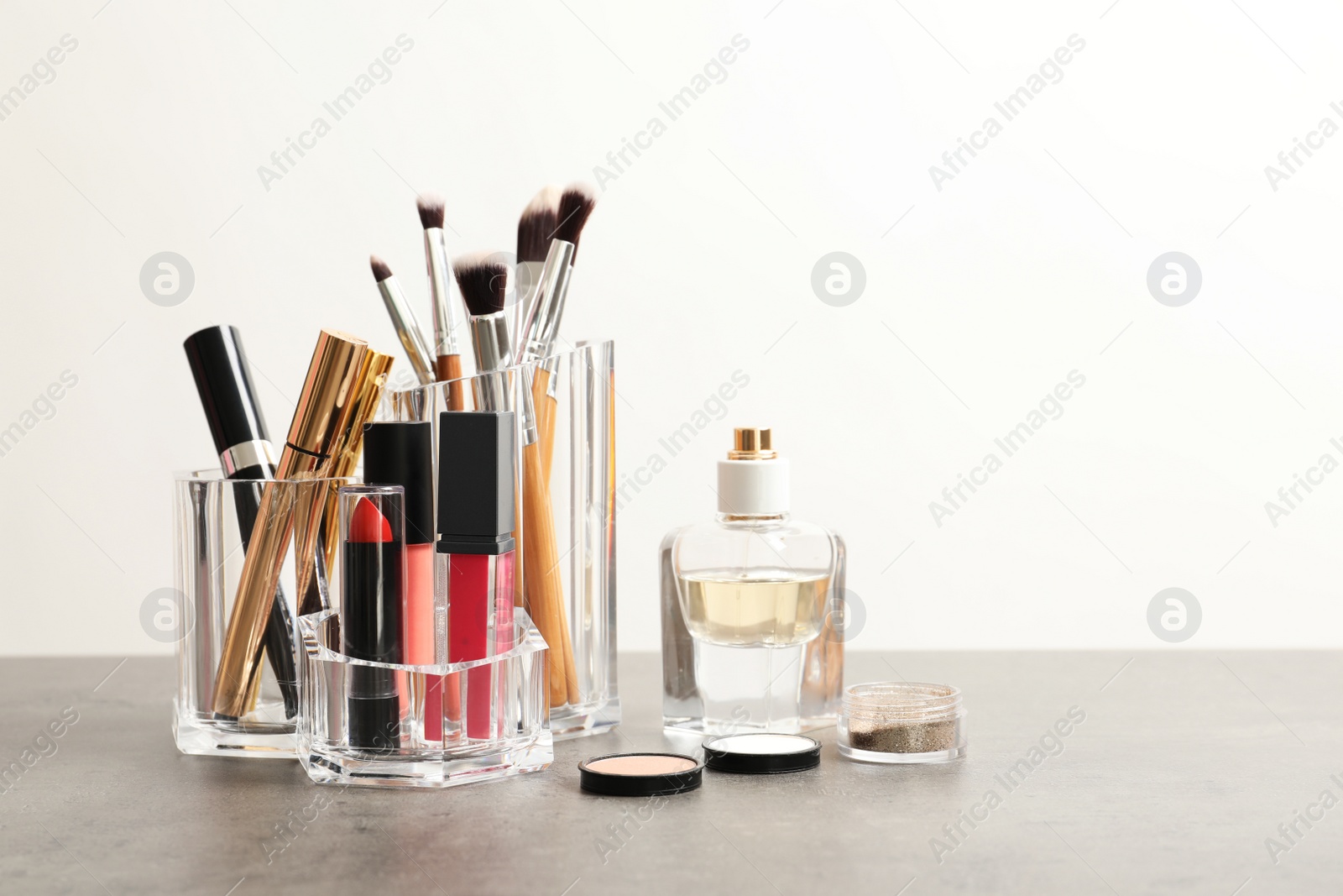 Photo of Lipstick holder with different makeup products on table against white background. Space for text