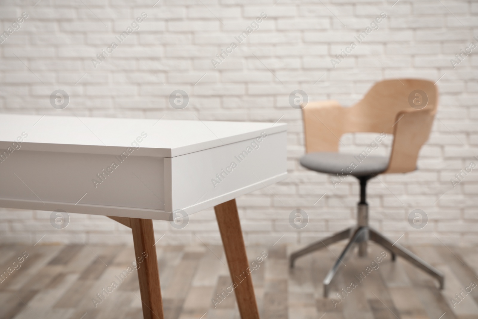 Photo of Stylish armchair near white brick wall indoors, focus on wooden table