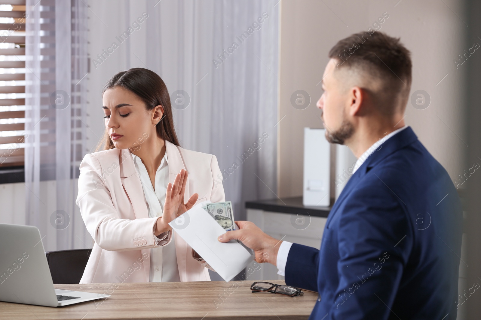 Photo of Businesswoman rejecting bribe at table in office